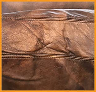 A Restoration Hardware backrest cushion showing cracking in areas stressed and creased from leaning back, highlighting lack of routine moisturizing. This couch needs our Leather Conditioning treatment. A Restoration Hardware backrest cushion showing cracking in areas stressed and creased from leaning back, highlighting lack of routine moisturizing. This couch needs our Leather Conditioning treatment.